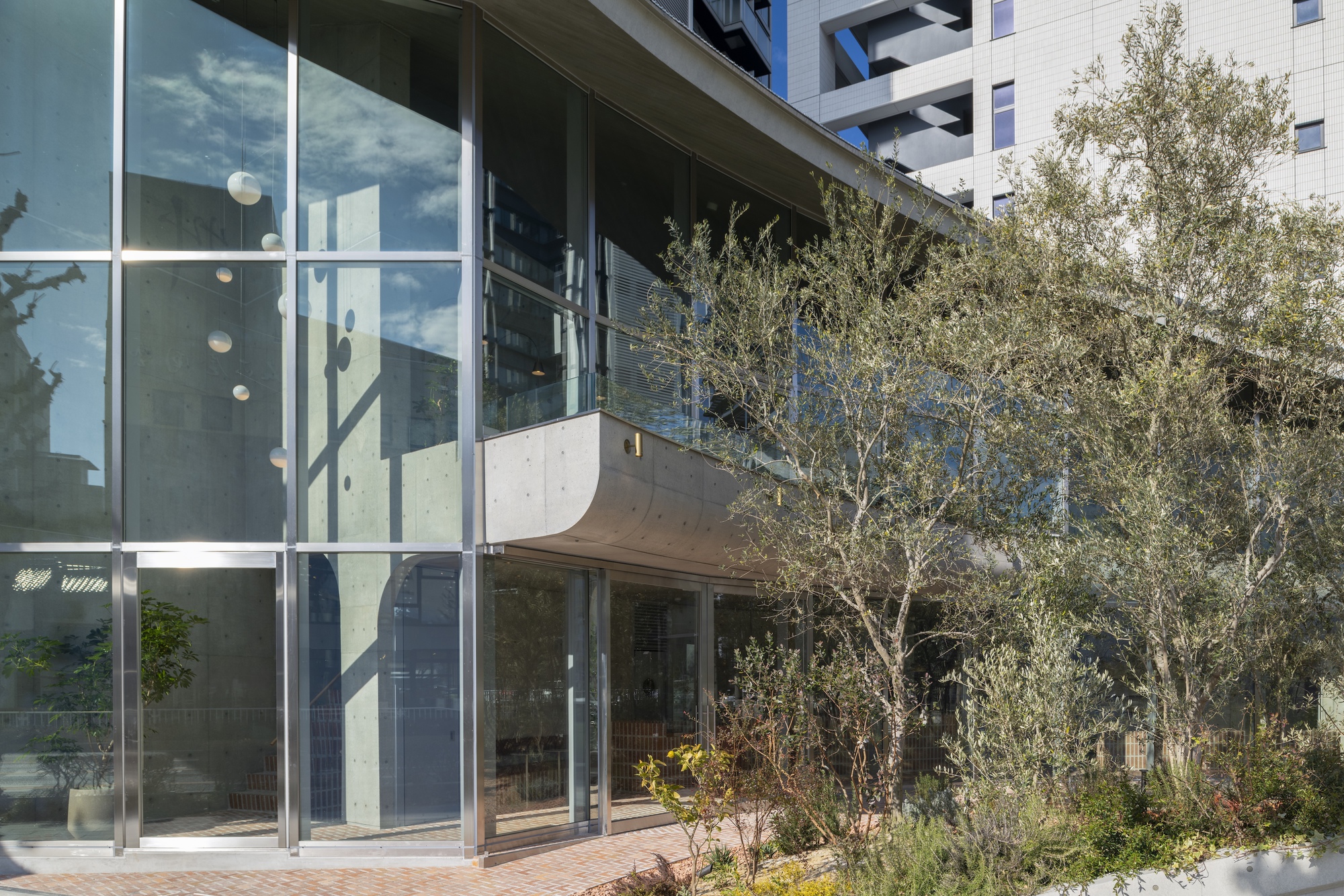 Glass facade and olive courtyard of AOI Celestie Coffee Roastery
