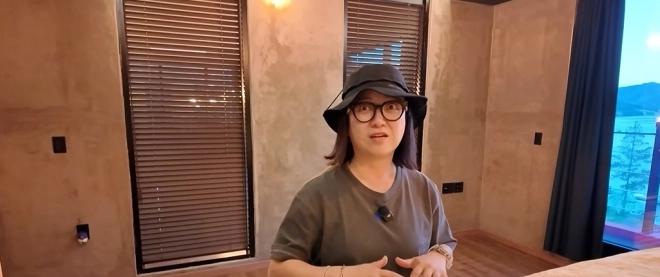 최여진이 침실에서 창밖 호수 풍경을 배경으로 이야기하고 있다