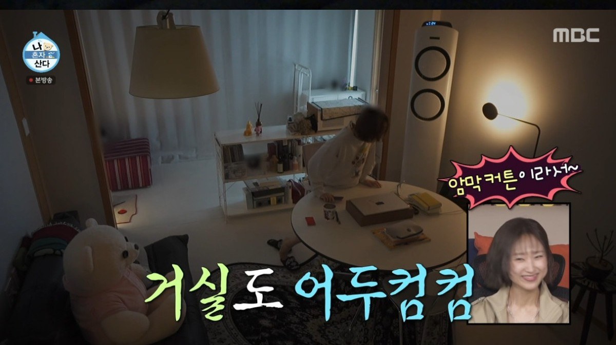 암막 커튼을 친 채 조명만 켜둔 어두운 거실과 원형 테이블
