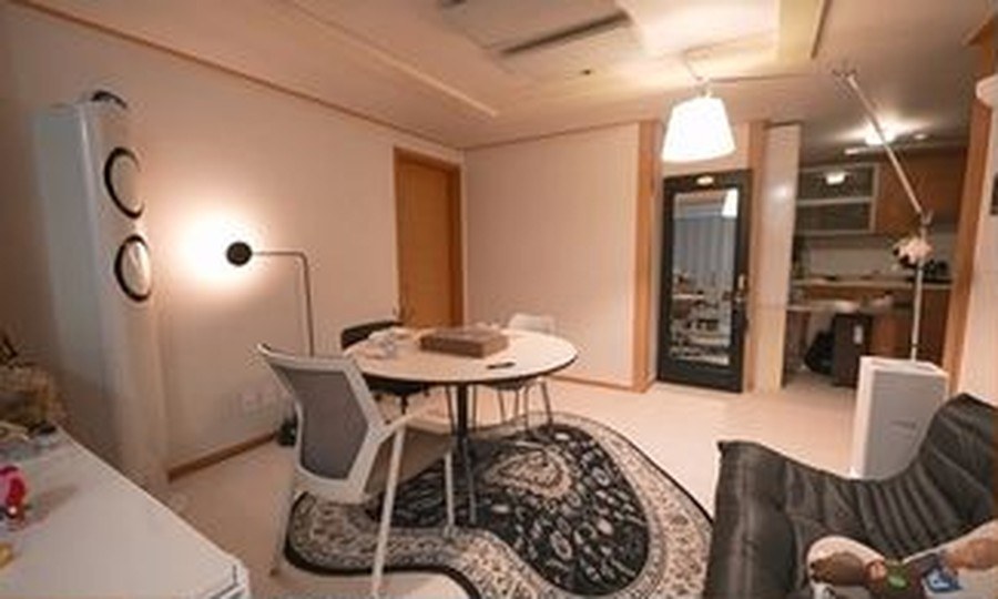 원형 테이블과 패턴 러그, 펜던트 조명이 놓인 거실 전경