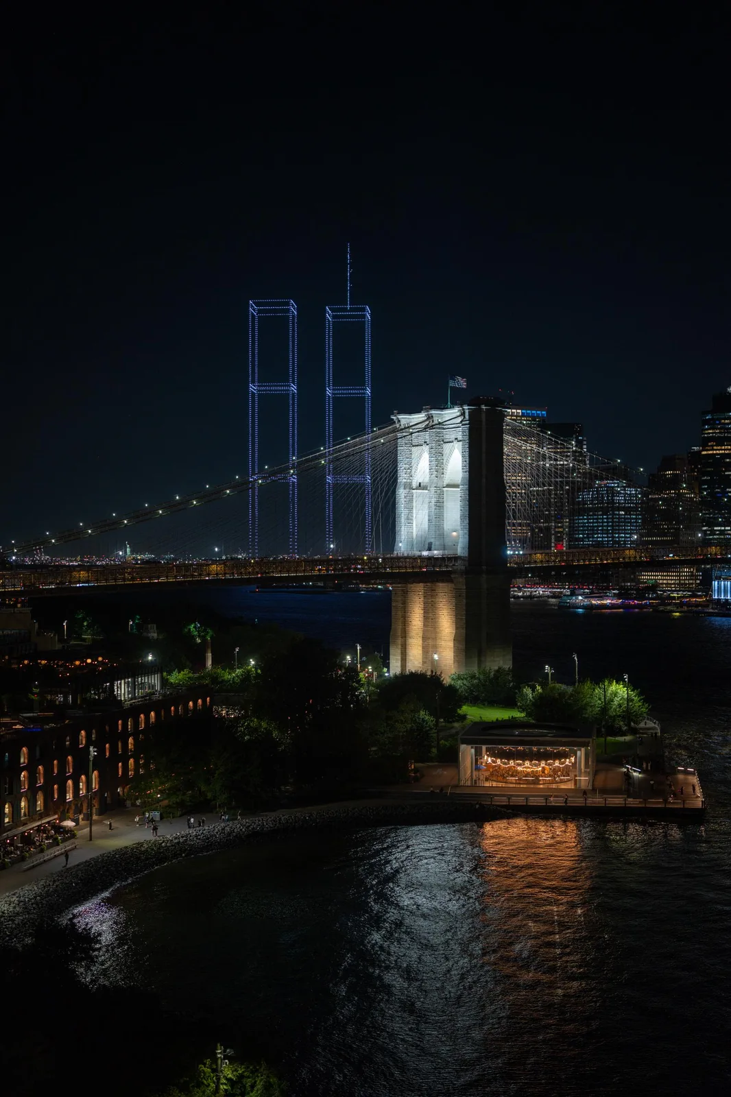 브루클린 브리지 너머로 드론이 그린 Twin Towers 실루엣이 떠 있다