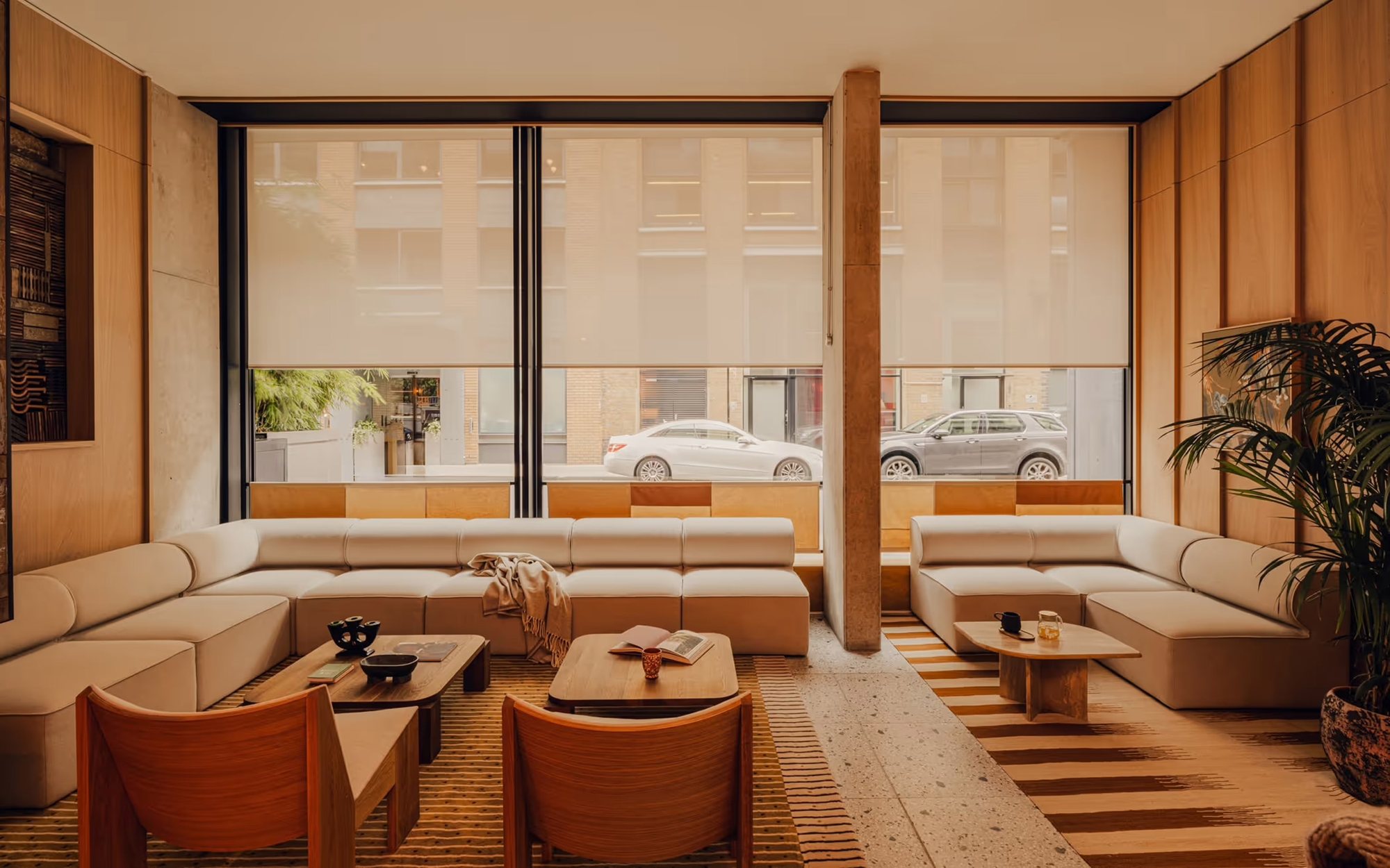 낮은 소파와 러그로 구역을 나눈 브라운 톤의 Aethos Shoreditch 로비 라운지