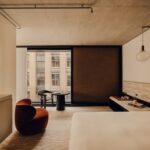 창가에 번트 오렌지 암체어를 둔 Aethos Shoreditch 객실