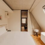 사선 창과 화이트 침구가 있는 Aethos Shoreditch 객실