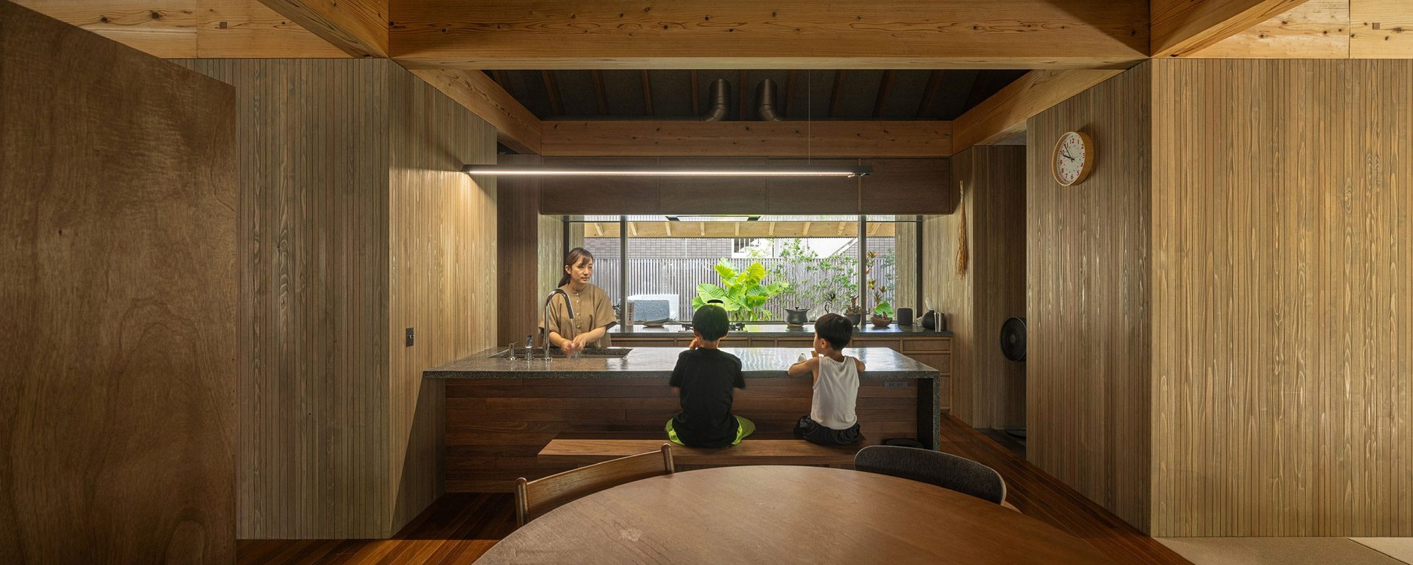 텃밭이 내다보이는 목조주택 주방에서 시간을 보내는 가족, Amami House