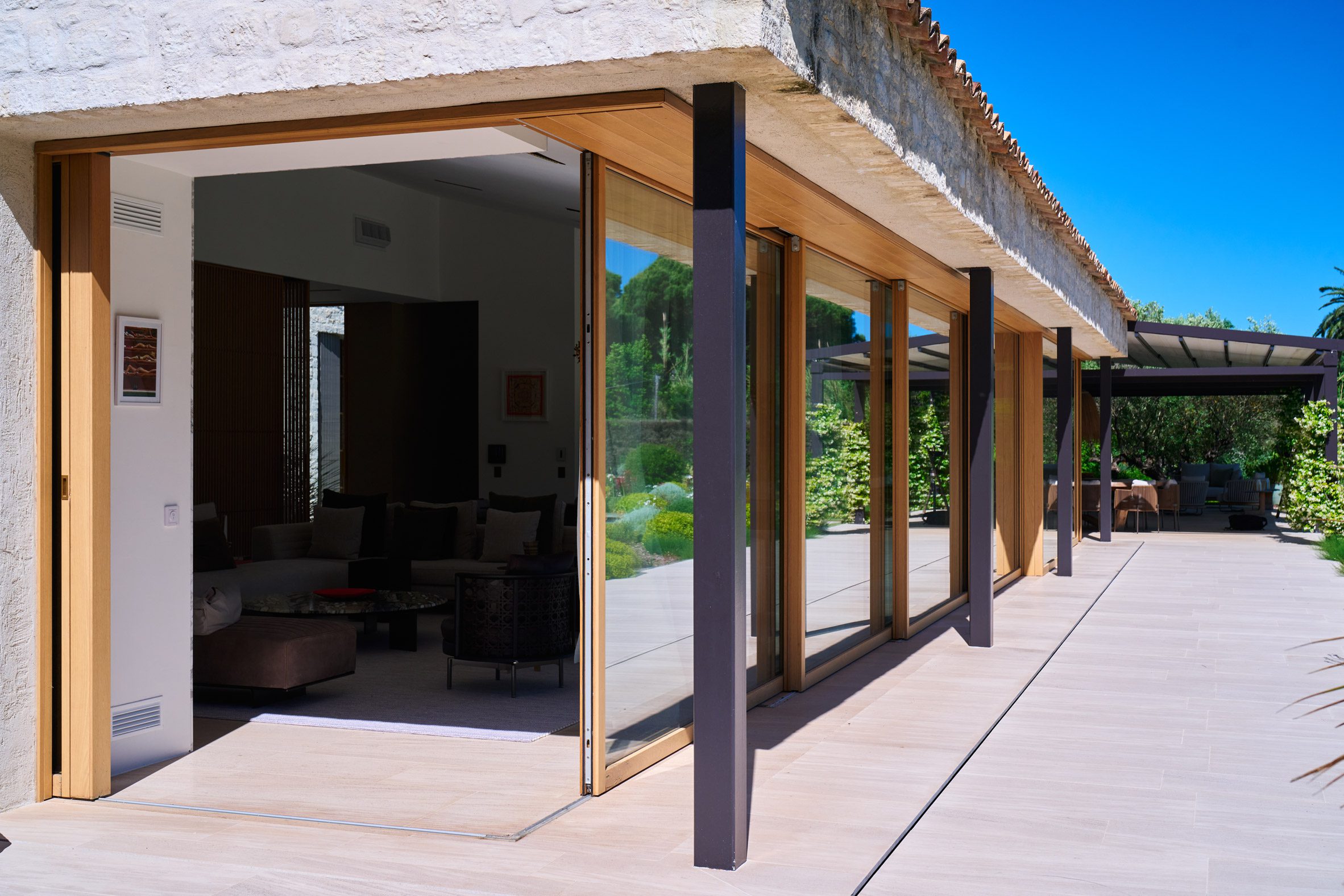 Villa Ramatuelle 모서리에서 양쪽으로 갈라져 열린 Carminati 리프트 슬라이딩 목재 창호