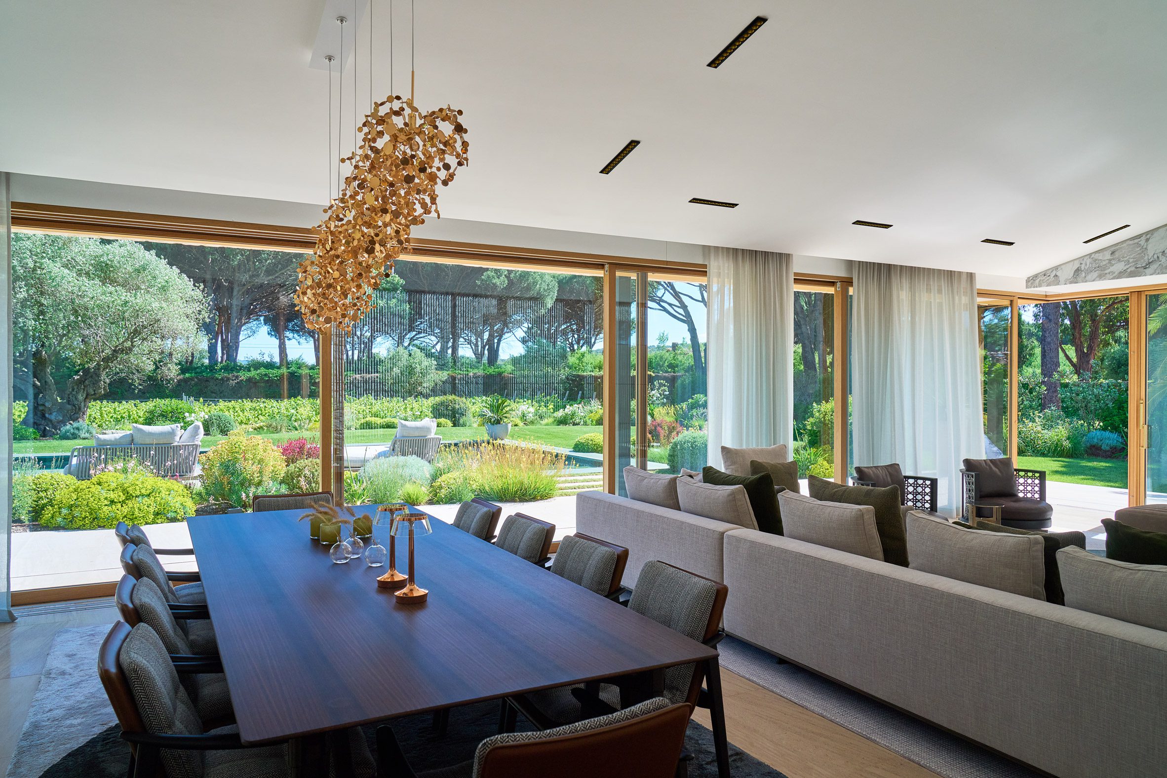 얇은 오크 프레임 목재 창호 너머로 정원이 보이는 Villa Ramatuelle 거실과 다이닝