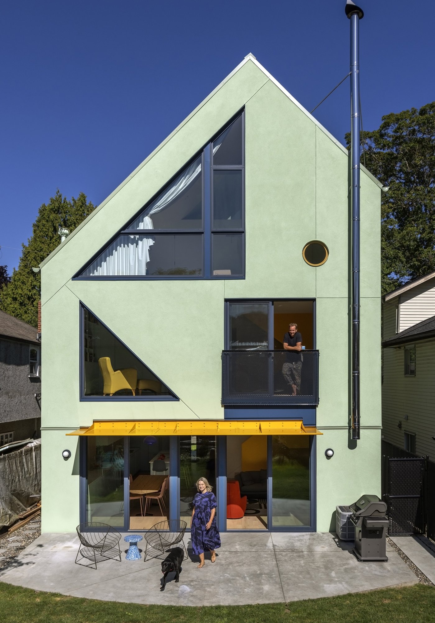 뒷마당 쪽 Fluevog House 후면 외관, 옐로우 차양과 큰 창
