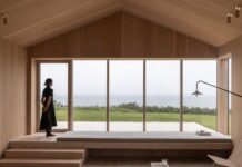 헛간 두 채를 어긋나게 붙였더니 마당이 생겼다, Heatherhill Beach House 창가 벤치에 앉아 바다를 바라보는 거실 공간
