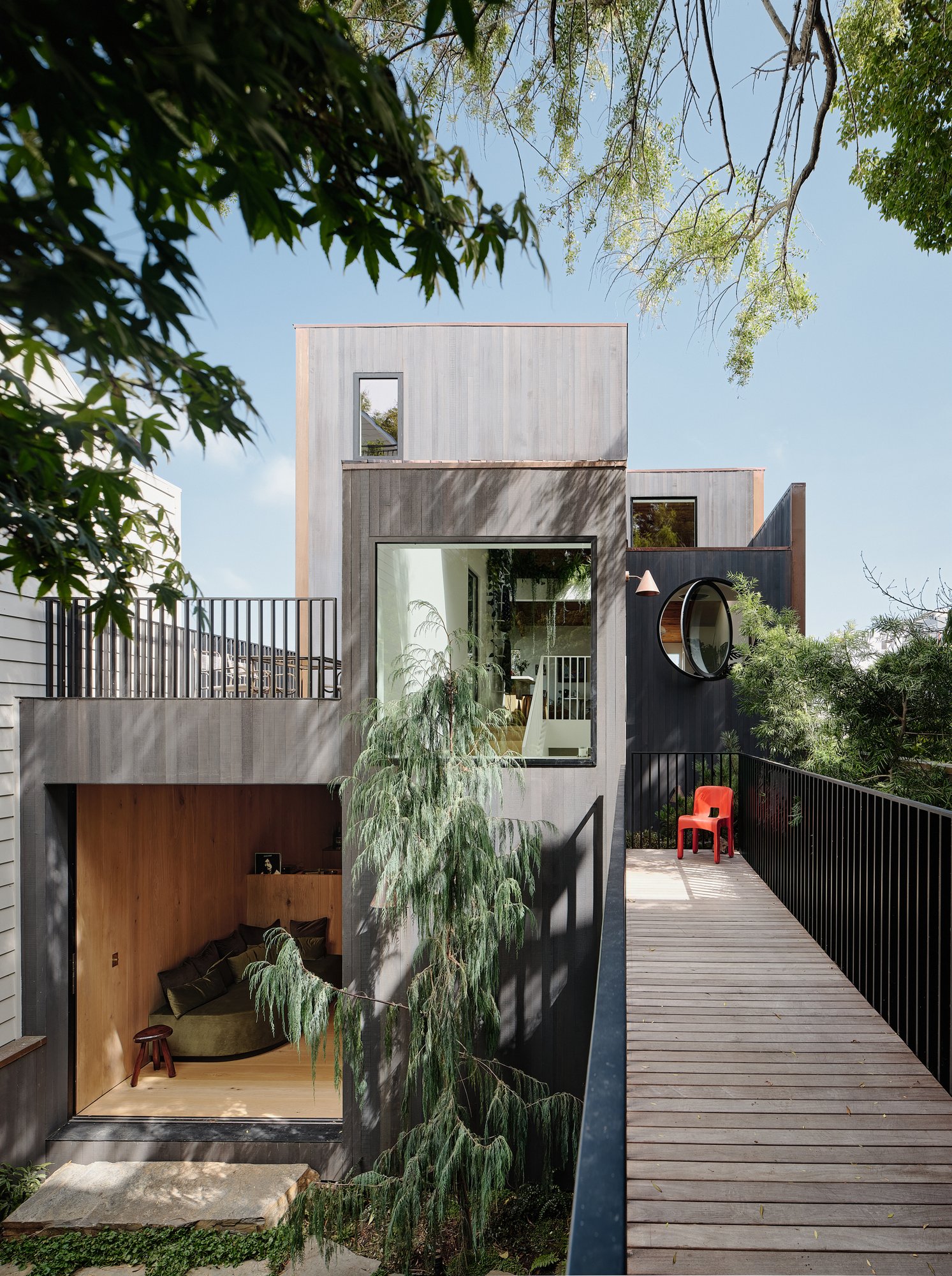 다리와 차콜 삼나무 외피, 개방된 라운지가 보이는 Hosono House 파사드