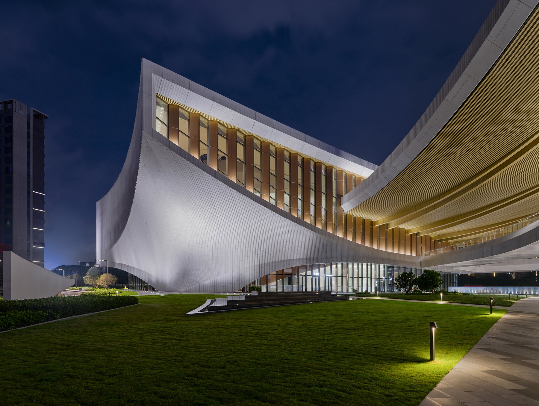 야간의 Songshan Lake Exhibition and Performance Centre 곡면 지붕과 잔디광장