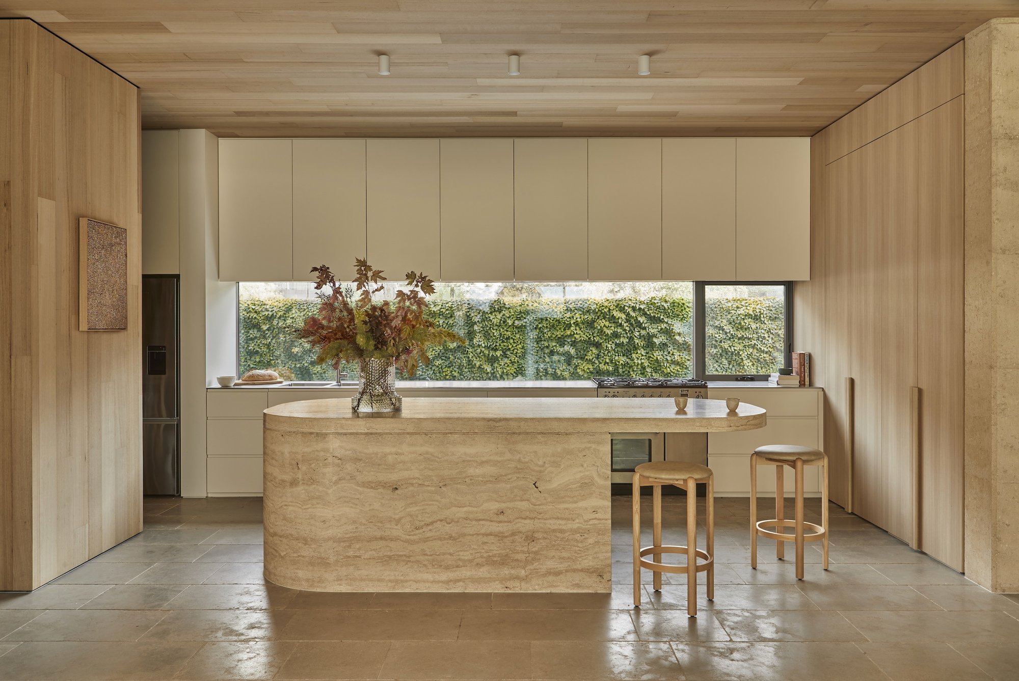 곡면 트래버틴 아일랜드와 가로로 긴 창을 낸 Barwon Dunes House 주방
