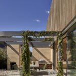 넝쿨 퍼걸러 너머로 보이는 Barwon Dunes House 목재 스크린 외관과 테라스