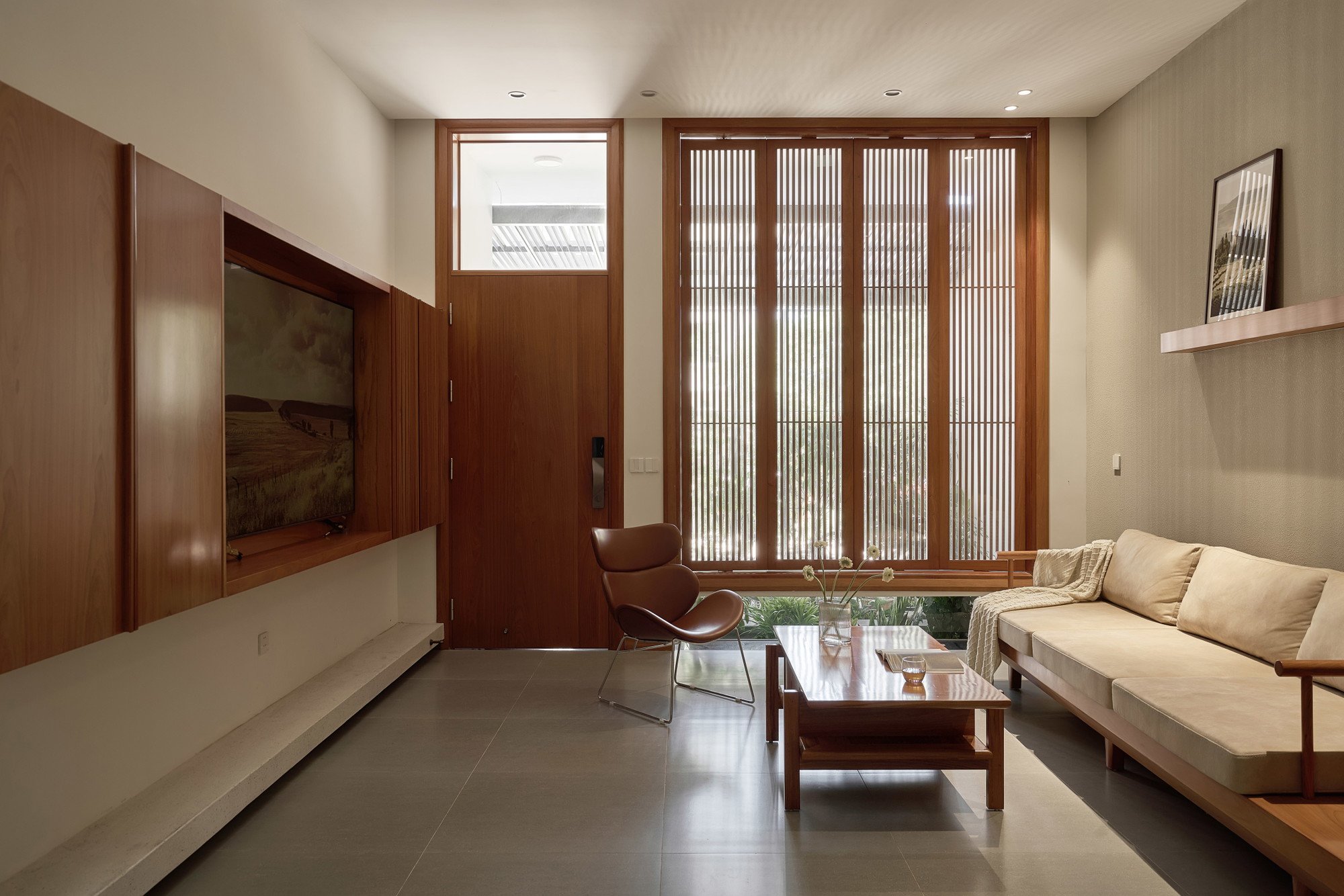 목재 붙박이 벽과 세로 살 창이 있는 PAMA House 거실