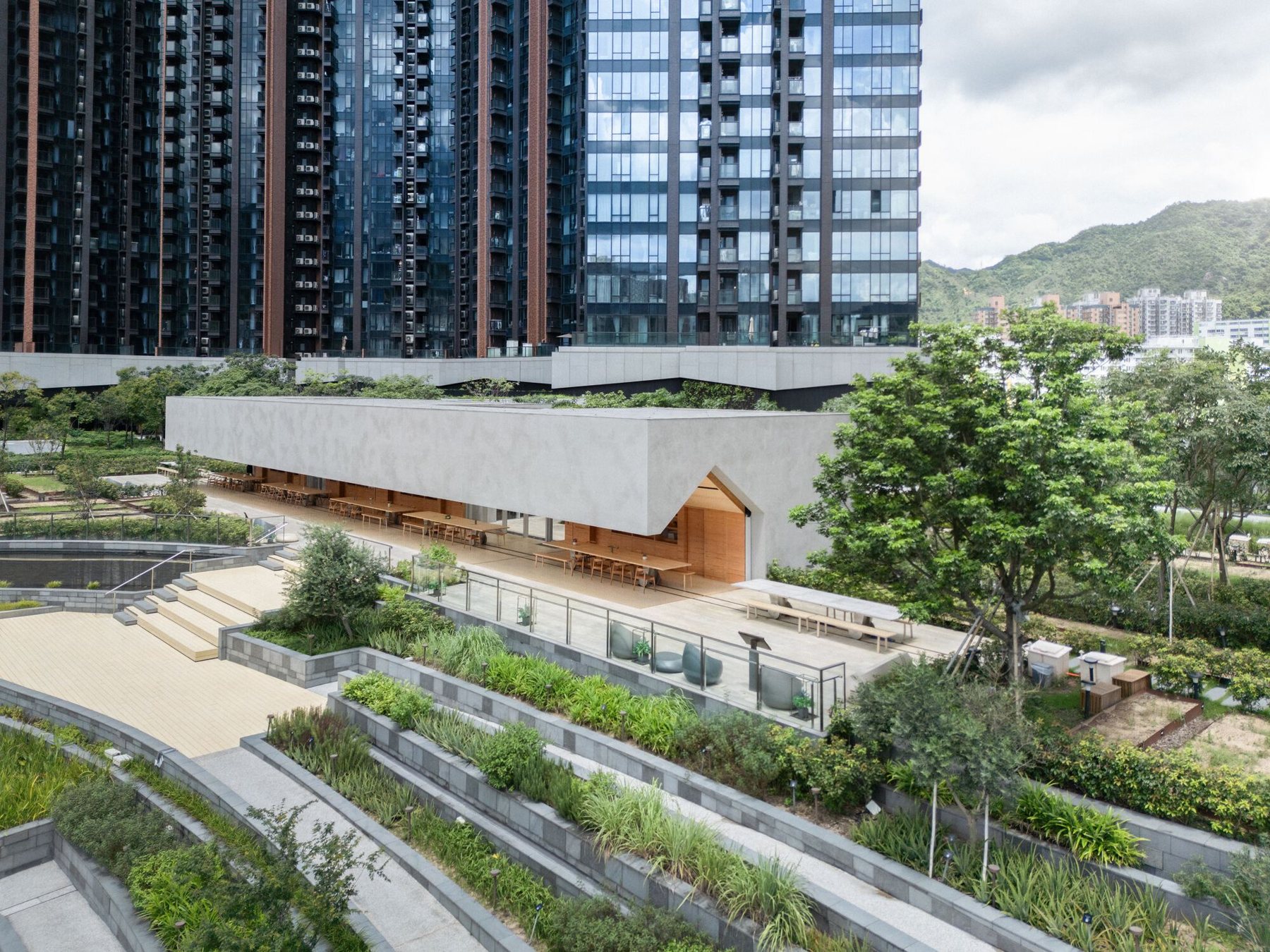 고층 아파트 타워 아래 계단식 텃밭 사이에 놓인 Pavilia Farm의 Farm House 외관