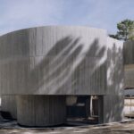 나무 그림자가 드리운 Trefoil House 곡면 콘크리트 매스